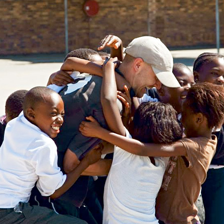 Student hugged by South African community children