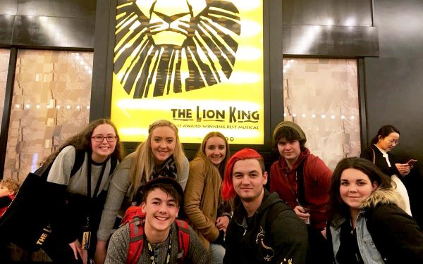 Students in front of poster for The Lion King musical