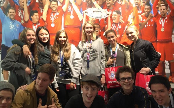 Students posing next to poster of Bayern Munich winning the Bundesliga