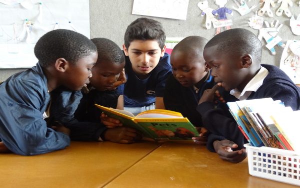 Boy reading to group of young students Service learning tour Cape Town South Africa
